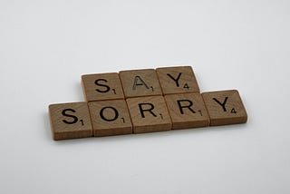 Scrabble tiles that spell out the words “Say Sorry”