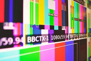 A close-up of a television screen showing coloured bar test patterns.