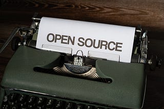 An Image by Markus Winkler of a typewriter typing out a paper that has Open-source boldly writing on it.