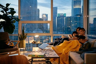 Photo of a family of five (two parents, three kids) reading together under a blanket on a couch in an Airbnb