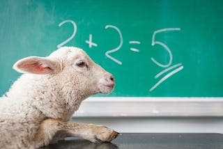 A green chalkboard in the background with 2+2 = 5 written on it, and a sheep with its foot on a table Ifront of it.