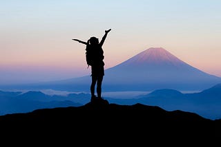 Woman on mounitain, view on another mountain, arms in the air