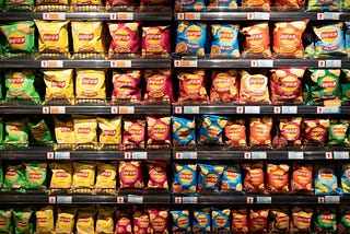 A photo of a wall of potato chip packages lined up on shelves with price tags.