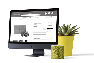 A mock up of the Fresh Crop Website on a Mac, with a plant and candle beside the screen.