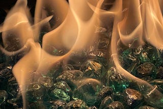 This is a photo of fire over shiny green stones.