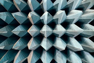 Large spiky 3-D metal points lined up next to each other and facing towards the viewer. It appears to be abstract shapes but is an image of the walls of an anechoic chamber.