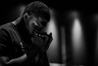 Man praying with his hands clasped together