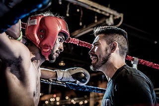 A coaching and a boxer in a boxing ring.