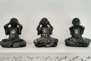 Photo shows three Buddha statues, one covering his eyes, one covering his ears, and one covering his mouth.