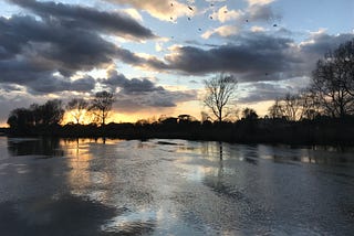 A slightly cloudy sky at sunset, reflected in the river