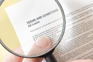 Photograph of a hand holding a magnifying glass over small text on a load document