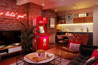 The KFC hotel room features a neon sign “it’s finger lickin’ good”, aa House of Harland cushion, a big TV, kitchen, sofas and of course a bucket of chicken