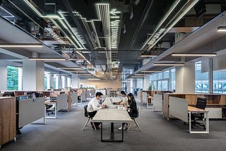 man and woman sit at a table in an open, modern office