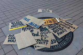 Protest signs from Oakland’s 2020 Juneteenth protest litter the ground of Frank Ogawa Plaza