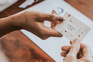 Two business owners passing a name card over a desk