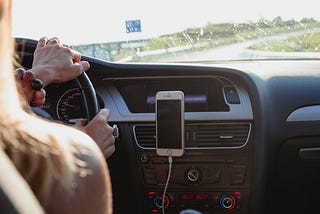 woman driving car listening to podcast on phone
