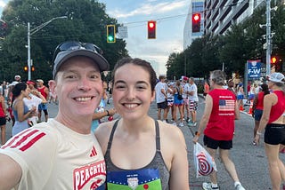 Father and daughter smile for the camera at the start line of a road race