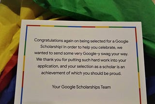 A Congratulations card from the Google team to Nandita , sitting on a bed of yellow, green, red and blue parchment paper.