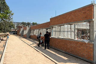 A building is under construction. There are some workers next to the building.