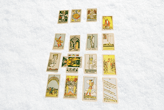 Background: White blanket Foreground: Seventeen Rider Waite tarot cards. Image by Gem Blackthorn