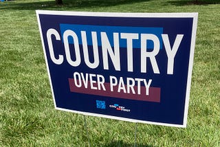 Yard sign, blue and red, saying “COUNTRY OVER PARTY,” with the word “Country” over and much larger than the rest. (Photo by author.)