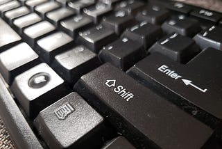 A close-up of a modern computer keyboard with the “shift” key in the foreground.