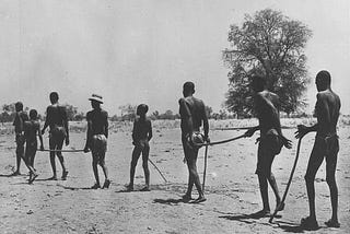 In Africa, blind adults are led through a desert-like environment by children.