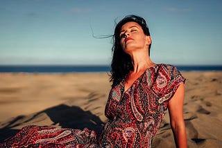 Woman wearing a beautiful dress while sunbathing at a Spanish beach. How moving to Spain changed my approach to health, fitness, and happiness