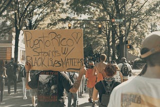 Protester with a sign saying “Puerto Rico stands with Black Lives Matter”