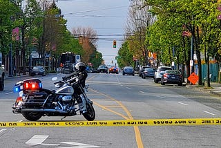 A Police motorcycle parked beyond a yellow warning tape in the middle of a street.