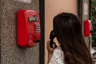 Woman making a phone call with a red payphone