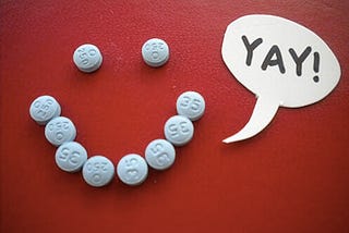 Birth control pills arranged in a smiley face with a speech bubble saying “yay!”