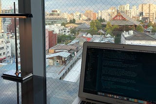 Picture of my computer with the HTML code for my distill.pub publication. Background is a window showing Tokyo, Japan.