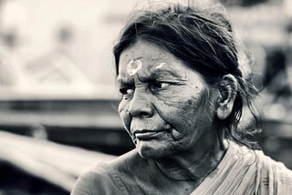 black and white photo of older brown-skin woman’s face as she looks towards the left with a slight frown