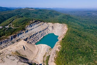 A reclaimed mining site surrounded by lush green forests.