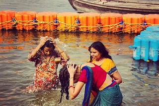 Three middle-aged ladies are bathing in the Gange river near Allahabad, India. They are dressed with colorful saris.