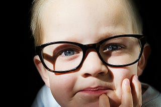 Little boy with glasses looking into camera