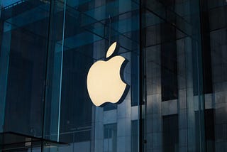 Apple company’s logo on a glass wall.