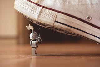 Tiny LEGO character being squashed by a human shoe