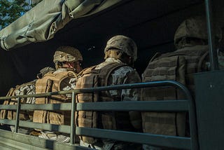 Uniformed soldiers sit in a truck.