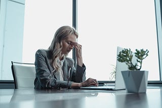 Woman sitting at her office desk with her hand on her face indicating she feels stressed