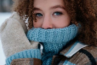 Young woman with blue eyes with sweater covering mouth