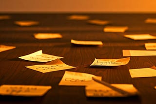 Orange toned image of sticky notes across a desk