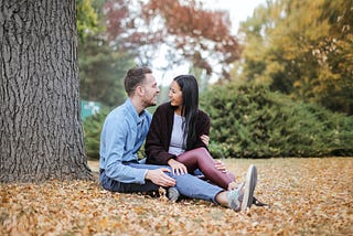 Couple sitting under tree talking