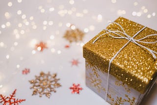 Holiday gift in glitter wrapping paper and glitter snowflakes