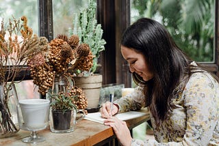 happy young woman writing at cozy desk