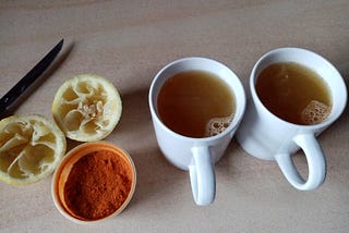 A surface with two squeezed lemon halves, Magic Mix and two mugs of Lemon “Tea”