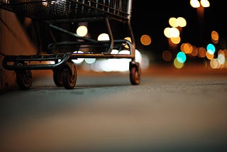 Foto das rodas de um carrinho de compras abandonado, como se você estivesse deitado no chão olhando para ele.