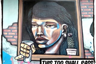 Street painting of a woman looking out a window in a brick wall. She’s holding a glass. The caption reads, “This too shall pass.”