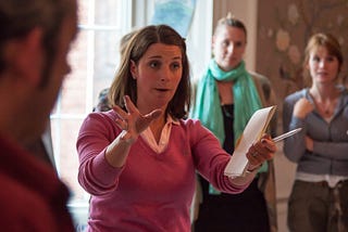 Young woman directing a group of people as they sing together